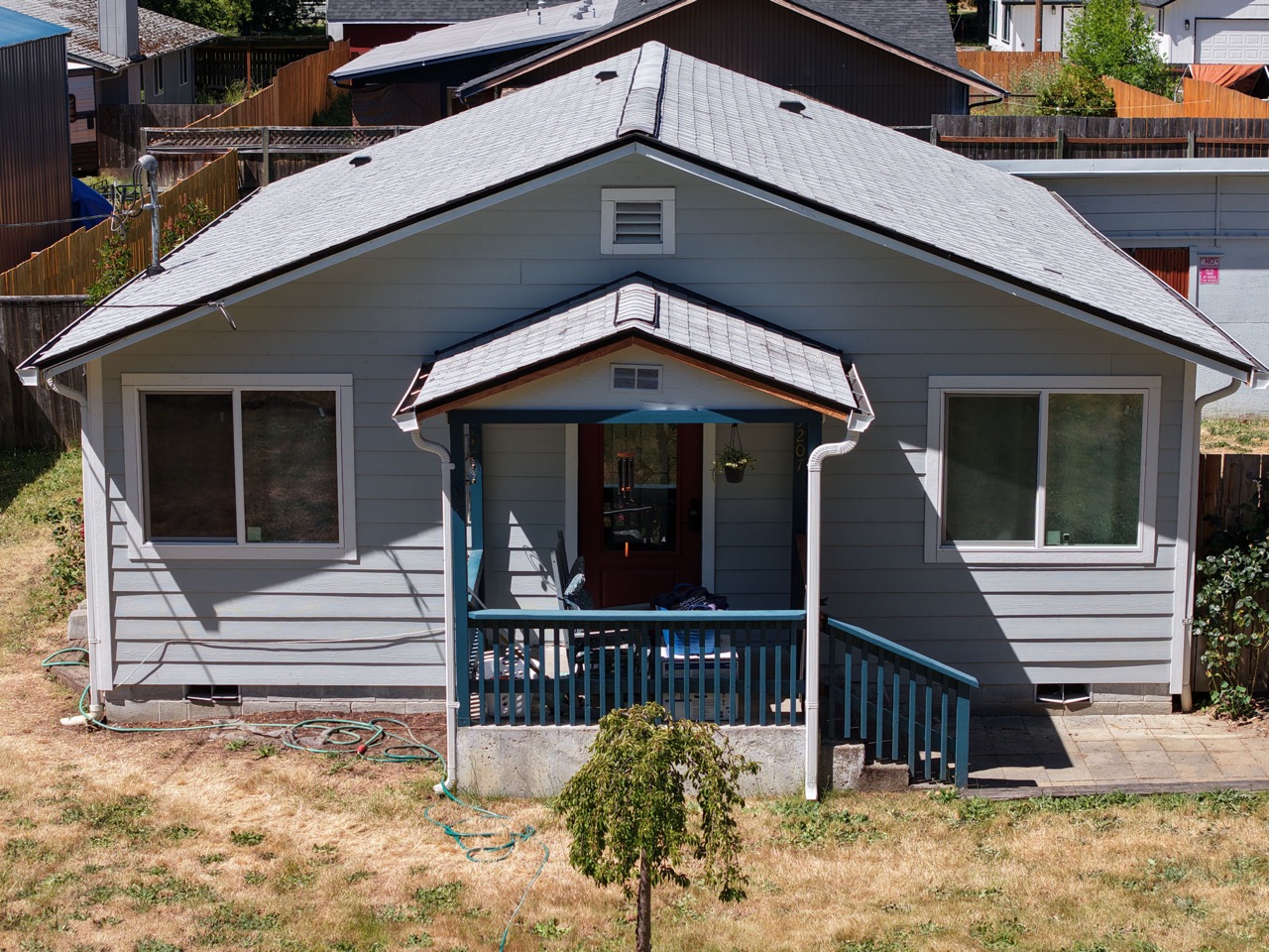 A light-gray bungalow with a new roof, lap siding, gutters, and a covered porch.